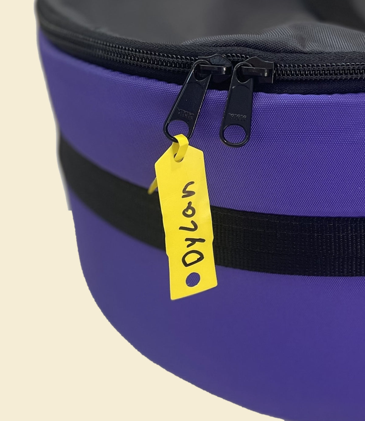 Dylan tag photo: Ruby Moons packing round dry bag with yellow name tag reading "Dylan," shown on a light beige background