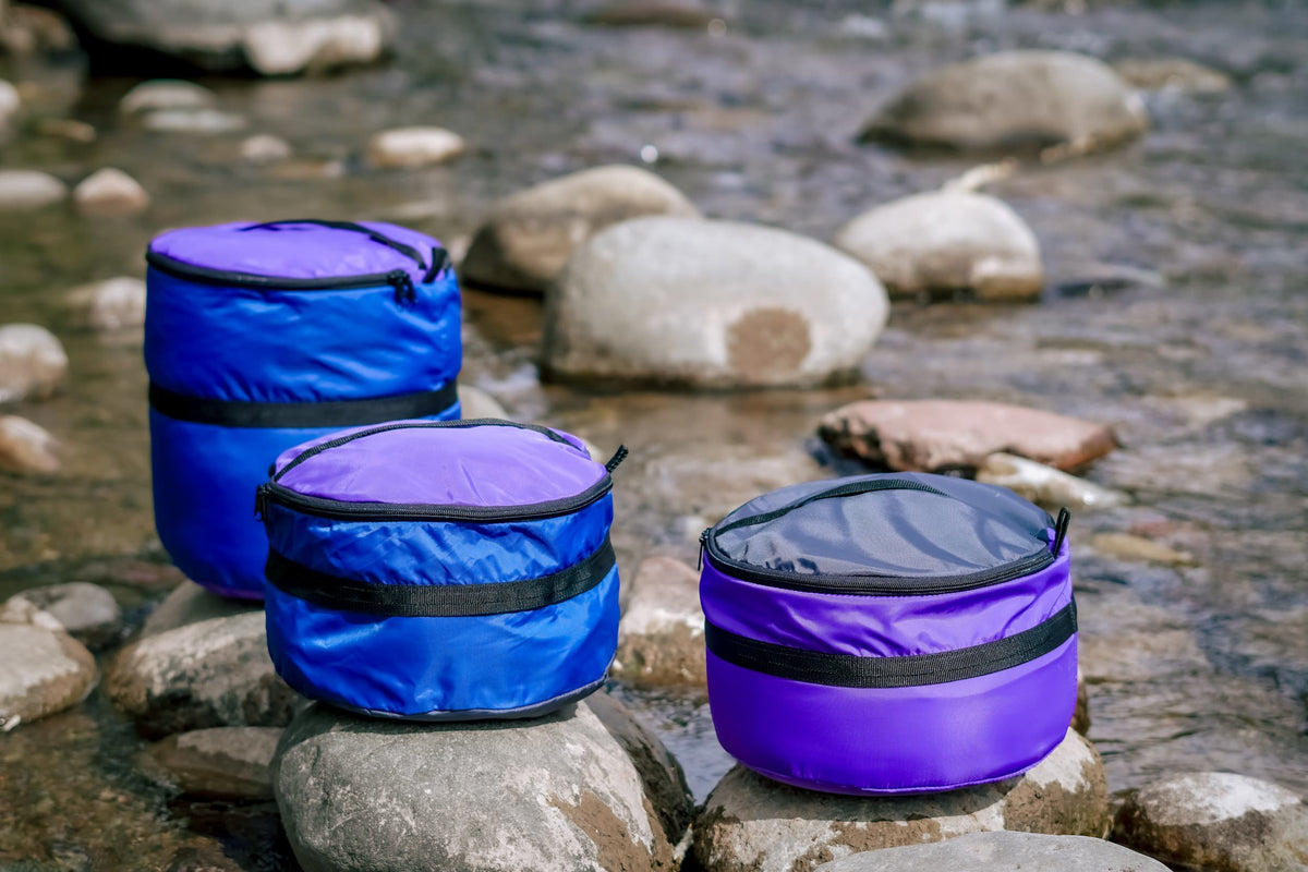 Three Ruby Moons packing rounds in blue and purple, set on rocks along a river