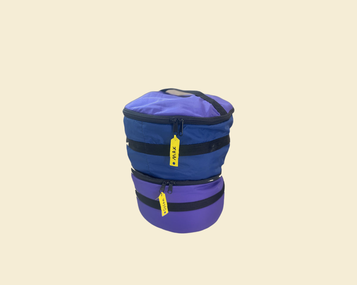 Two Ruby Moons packing round dry bags stacked together, with yellow name tags reading "Max" and "Dylan," shown on a light beige background